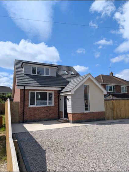 Detached new-build house with brick, render and grey cladding and a gravel drive
