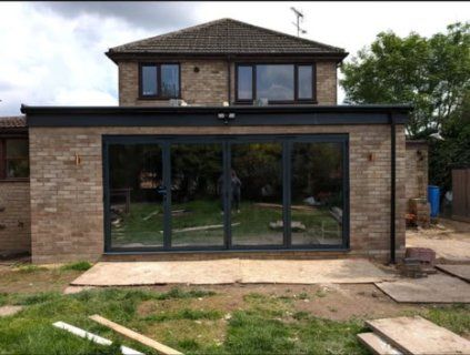 Buff-brick flat-roof extension with full-width dark grey bifold doors