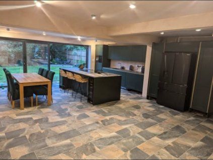 Open-plan kitchen-diner after a knock-through, with an island and slate-effect floor