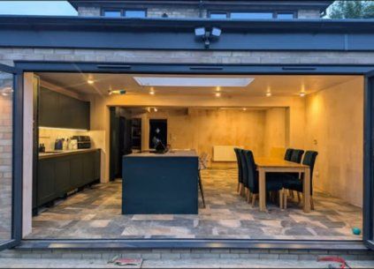 Open bifold doors into a kitchen-diner extension at dusk